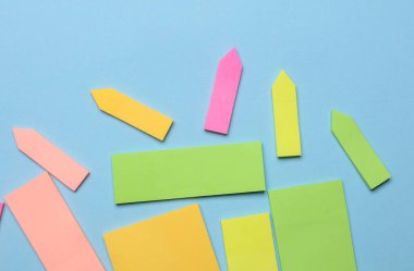 Çeşitli boş kağıt çıkartmaları var. Çok renkli. Mavi arkaplanda yapışkan not koleksiyonu