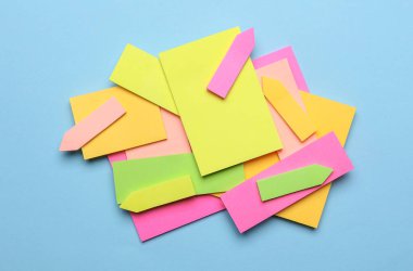 Çeşitli boş kağıt çıkartmaları var. Çok renkli. Mavi arkaplanda yapışkan not koleksiyonu