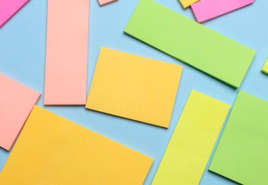 Çeşitli boş kağıt çıkartmaları var. Çok renkli. Mavi arkaplanda yapışkan not koleksiyonu