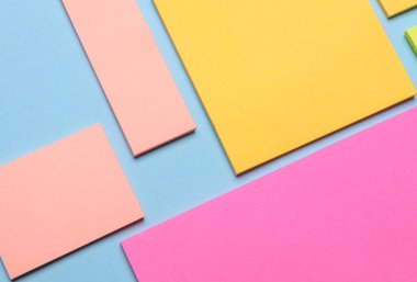 Çeşitli boş kağıt çıkartmaları var. Çok renkli. Mavi arkaplanda yapışkan not koleksiyonu