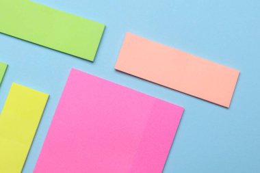 Çeşitli boş kağıt çıkartmaları var. Çok renkli. Mavi arkaplanda yapışkan not koleksiyonu