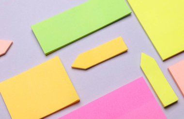 Çeşitli boş kağıt çıkartmaları var. Çok renkli. Gri arkaplanda yapışkan not koleksiyonu