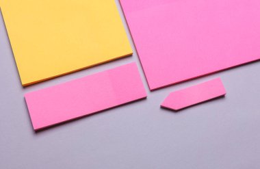 Çeşitli boş kağıt çıkartmaları var. Çok renkli. Gri arkaplanda yapışkan not koleksiyonu