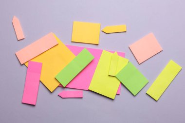 Çeşitli boş kağıt çıkartmaları var. Çok renkli. Gri arkaplanda yapışkan not koleksiyonu