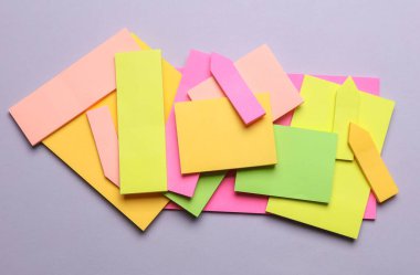 Çeşitli boş kağıt çıkartmaları var. Çok renkli. Gri arkaplanda yapışkan not koleksiyonu