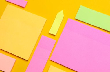 Çeşitli boş kağıt çıkartmaları var. Çok renkli. Sarı arkaplanda yapışkan not koleksiyonu