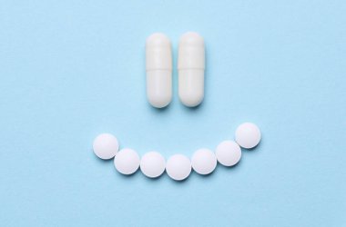 Mavi arka planda turuncu haplarla gülen surat. Sağlık ve İlaç Hizmetleri