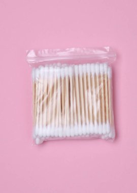 Kulakları temizlemek için pamuk çubuklar ya da pembe arka planda makyaj malzemesi. Eko kavramı