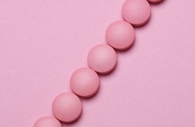 Pastel arka planda bir grup pembe hap.