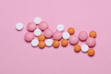 Pembe arka planda bir grup renkli hap.