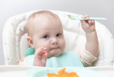 Beslenme masasında sağlıklı yemek yiyen şirin bir bebek.