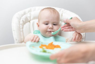 Annem bebeği kaşıkla besliyor.