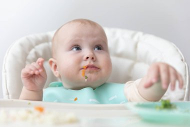 Beslenme masasında sağlıklı yemek yiyen şirin bir bebek.