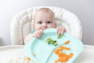 Beslenme masasında sağlıklı yemek yiyen şirin bir bebek.