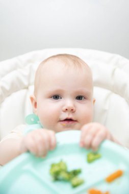 Beslenme masasında sağlıklı yemek yiyen şirin bir bebek.