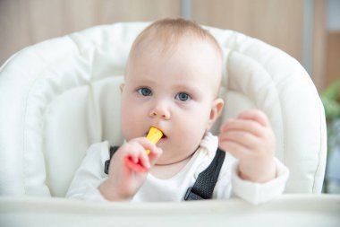 Sevimli bebek kaşıkla yemek masasında oturuyor.