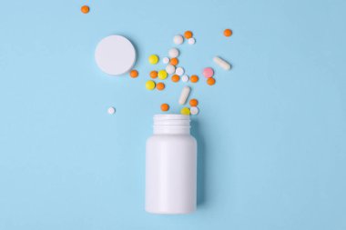 Mavi arka planda hapları olan beyaz plastik şişe. Tıp konsepti. Tasarım için model