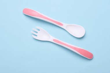 Mavi arka planda bebek beslemek için plastik çatal ve kaşık