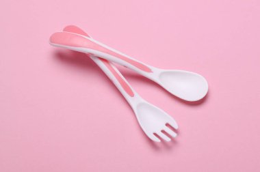 Pembe arka planda bebek beslemek için plastik çatal ve kaşık