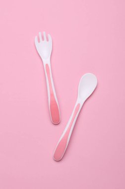 Pembe arka planda bebek beslemek için plastik çatal ve kaşık