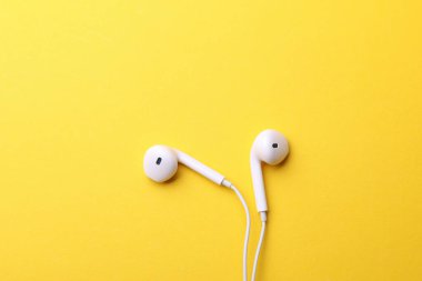 Sarı arka planda kablolu beyaz kulaklıklar