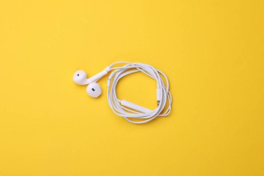 Sarı arka planda kablolu beyaz kulaklıklar