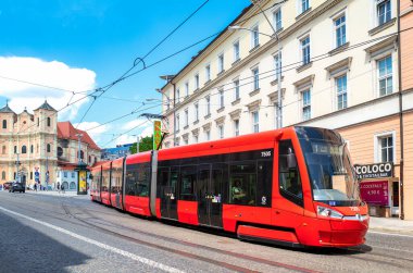 Bratislava, Slovakya - 8 Temmuz 2019: Arka planda Trinitarian kilisesi olan eski bir kasabada uzun kırmızı bir tramvay