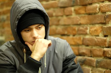 Kahverengi tuğla duvar arka plan kaputa bir yirmi yaşındaki çocuk portresi