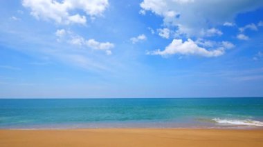 Deniz dalgaları, kumlu sahil ve mavi gökyüzü olan pitoresk bir marina.