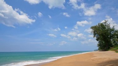 Deniz dalgaları, kumlu sahil ve mavi gökyüzü olan pitoresk bir marina.