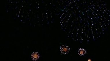 Karanlık gece gökyüzünde parlayan renkli havai fişeklerin 4K videosu