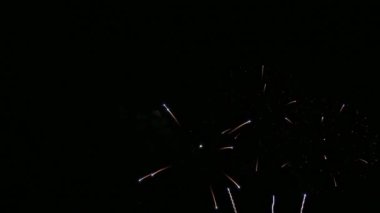 Karanlık gece gökyüzünde parlayan renkli havai fişeklerin 4K videosu