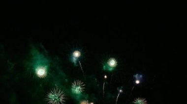 Karanlık gece gökyüzünde parlayan renkli havai fişeklerin 4K videosu
