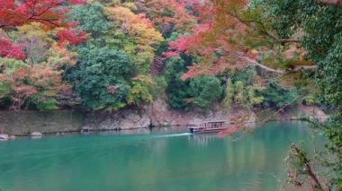 KYOTO, JAPONYA - 15 Kasım 2018: kayıkçı nehirde tekneye biniyor. Sonbahar mevsiminde Arashiyama, Kyoto, Japonya