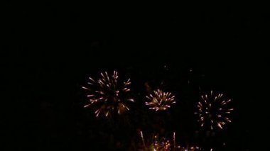 Karanlık gece gökyüzünde parlayan renkli havai fişeklerin 4K videosu