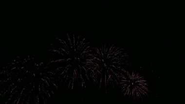 Karanlık gece gökyüzünde parlayan renkli havai fişeklerin 4K videosu