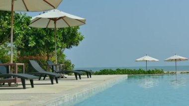 Yüzme Havuzu, plaj şemsiyeleri ve yemyeşil tropik bitki örtüsü 