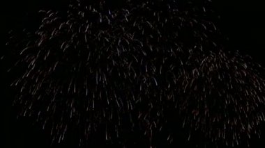 Karanlık gece gökyüzünde parlayan renkli havai fişeklerin 4K videosu