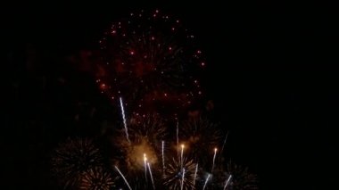Karanlık gece gökyüzünde parlayan renkli havai fişeklerin 4K videosu
