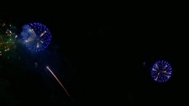 Karanlık gece gökyüzünde parlayan renkli havai fişeklerin 4K videosu