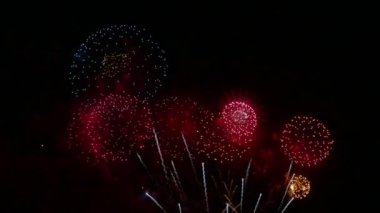 Karanlık gece gökyüzünde parlayan renkli havai fişeklerin 4K videosu