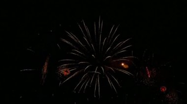 Karanlık gece gökyüzünde parlayan renkli havai fişeklerin 4K videosu