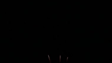 Karanlık gece gökyüzünde parlayan renkli havai fişeklerin 4K videosu