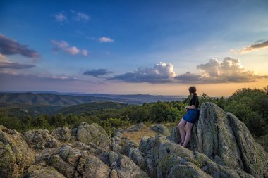 Genç bir kız tepeden güzel bir manzaranın tadını çıkarır. Dağlarda gezin..