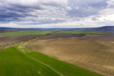 Güzel yeşil kırsal, tarlaların, yolların ve bulutlu gökyüzünün insansız hava aracından inanılmaz geniş hava manzarası.