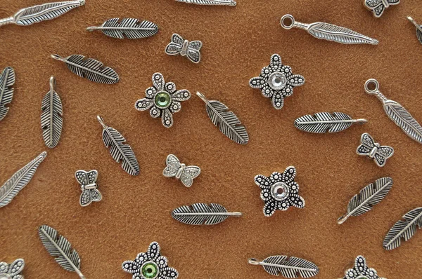 Colgantes y plumas de perlas de metal en ante marrón — Foto de Stock