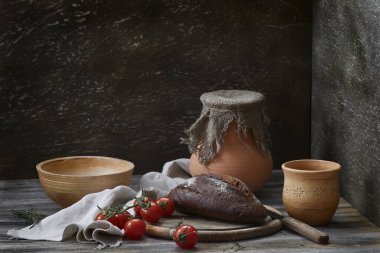 Kırsal bir hayat sürüyor. Seramik tabaklar, domatesler ve ahşap bir masada bir ekmek..