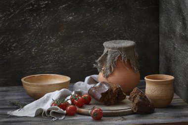 Kırsal bir hayat sürüyor. Seramik tabaklar, domatesler ve ahşap bir masada bir ekmek..