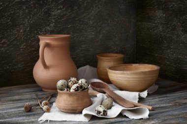 Still life in a rustic style. Quail eggs and set of ceramic dishes on a wooden table.