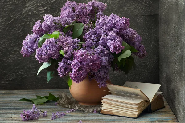 Stillleben Fliederstrauß Einer Tonkanne Und Ein Aufgeschlagenes Buch Auf Einem — Stockfoto